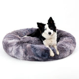 Dog lying on a fluffy gray pet bed against a white background