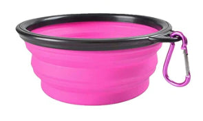 Pink silicone travel bowl with black rim and carabiner on a white background
