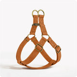 Brown leather dog harness with gold hardware on a white background