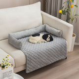 Dog lying on a gray pet bed attached to a beige sofa in a living room.