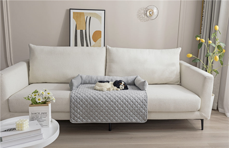 Dog lying on a quilted pet bed placed on a sofa in a living room.