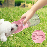 Pink pet water bowl with paw design on grass, close-up of bowl shown.