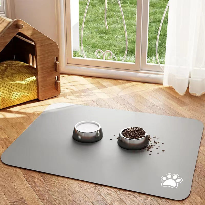 Gray pet mat with two bowls on a wooden floor near a window with green grass outside.