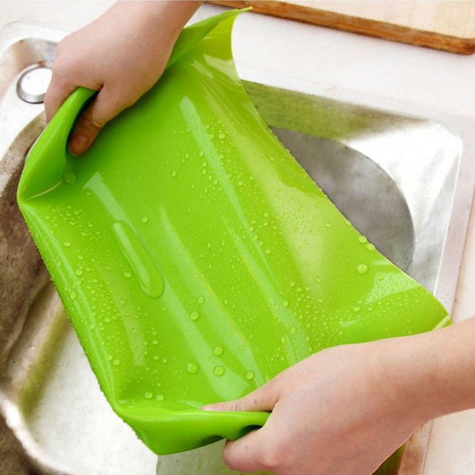 Green silicone mat being held over a sink
