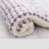 Folded blanket with pink, white, and gray pattern on a white surface