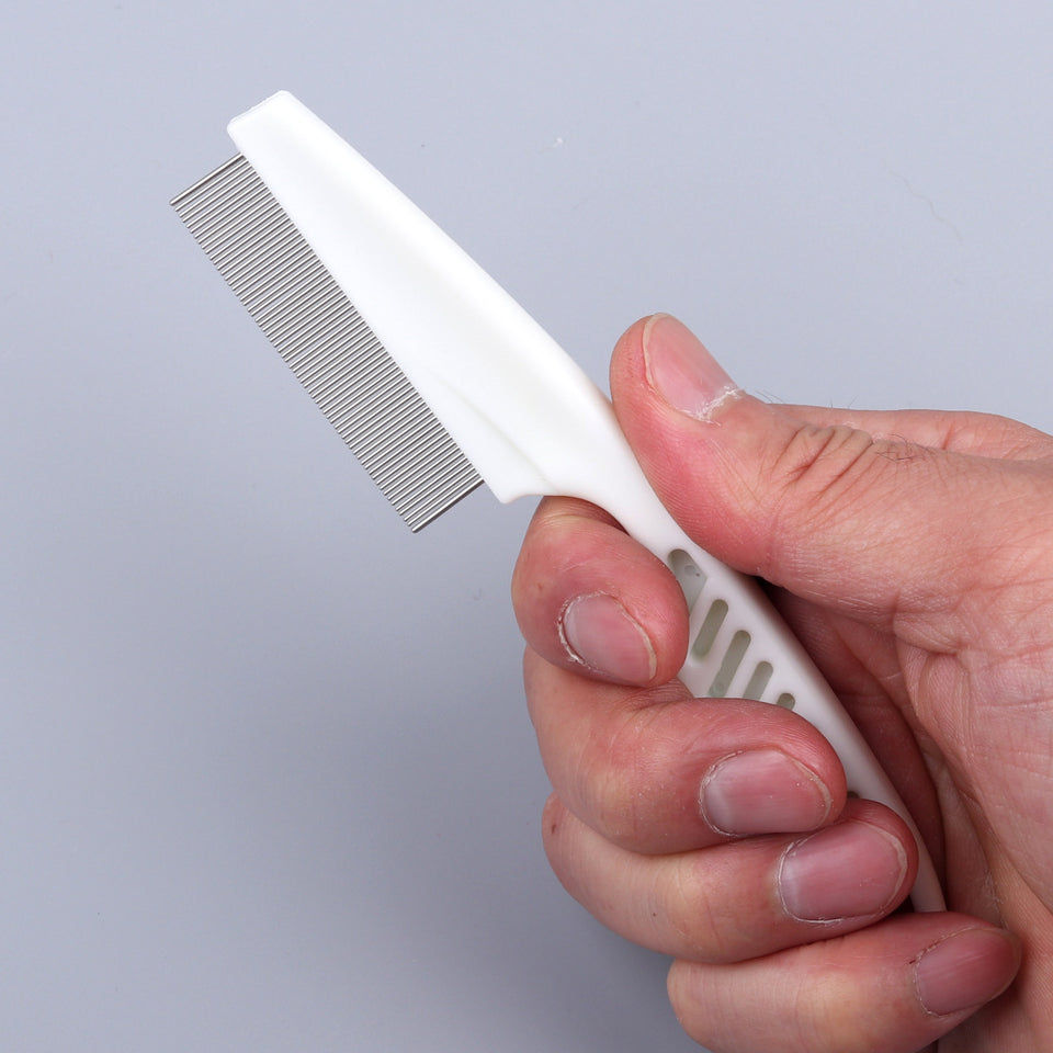 Hand holding a white comb with metal teeth against a gray background