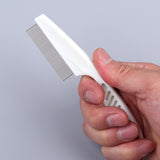 Hand holding a white comb with metal teeth against a gray background