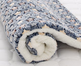 Rolled-up fleece blanket with blue and beige pattern on a white background