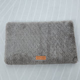 Folded gray textured blanket with a brand label on a white background