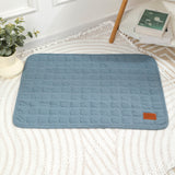 Blue textured bath mat on a white rug with a plant and books in the background