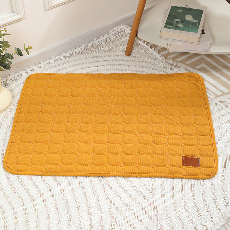 Yellow quilted mat on a white textured surface with a chair and books in the background.