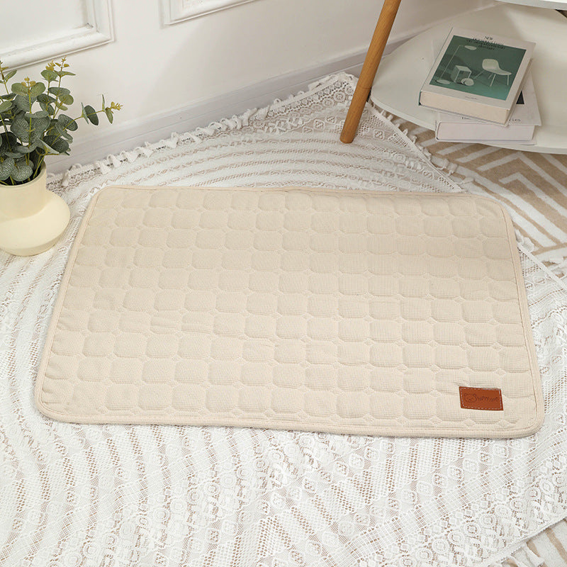 Beige quilted mat on a textured floor with a plant and books in the background