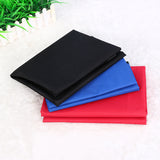 Black, blue, and red towels stacked on a white surface with grass in the corner.