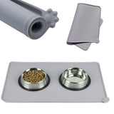 Pet feeding station with two bowls, a mat, and a roll of paper towels on a white background