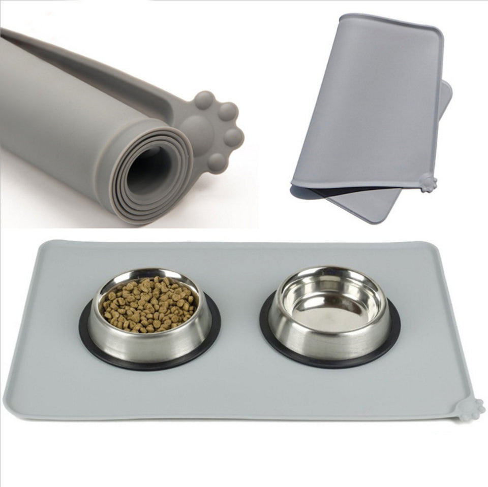 Gray silicone mat with two metal bowls containing pet food, rolled mat, and folded mat on a white background.